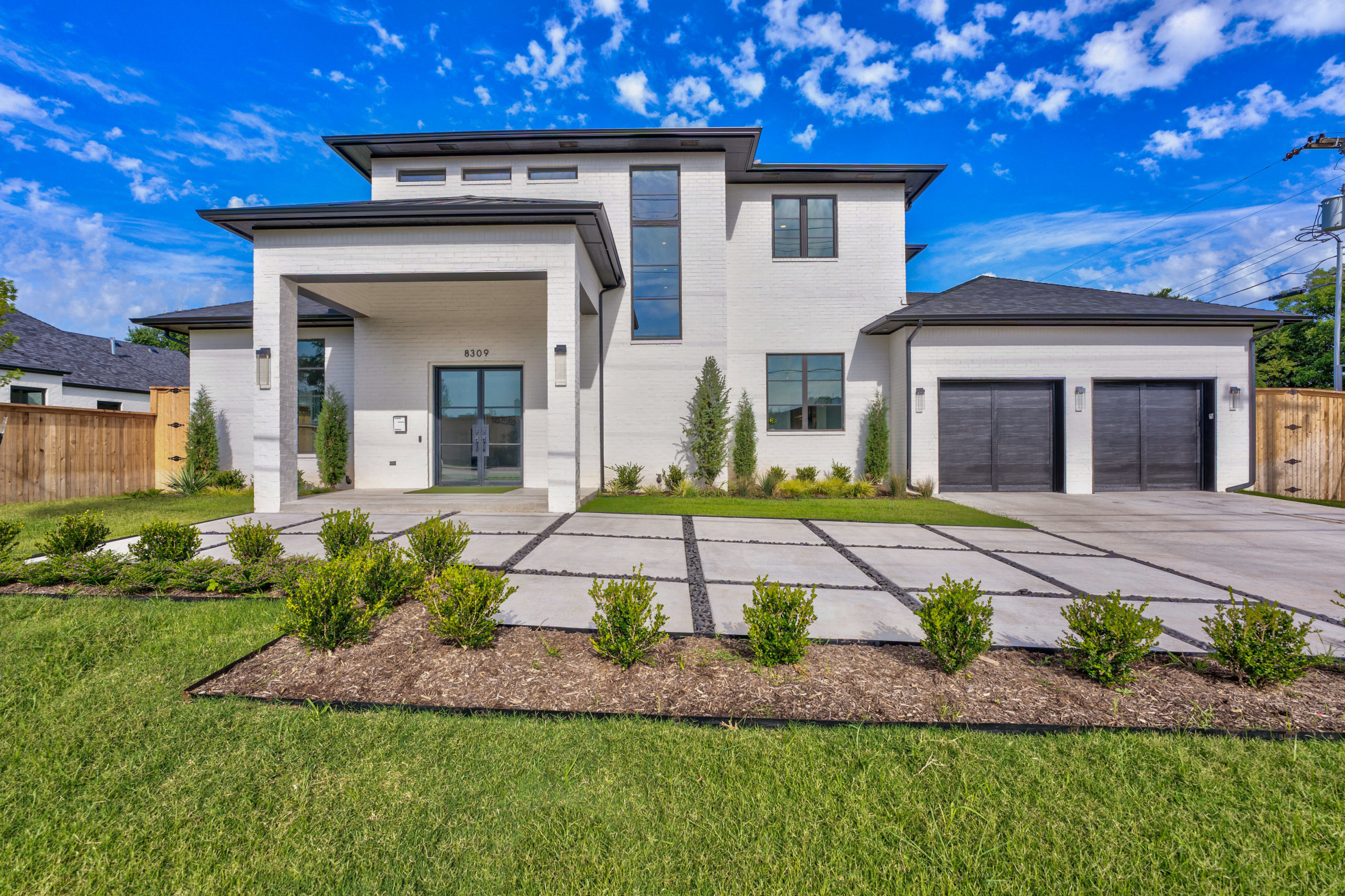 real estate photo of a large white house with two garages on the front