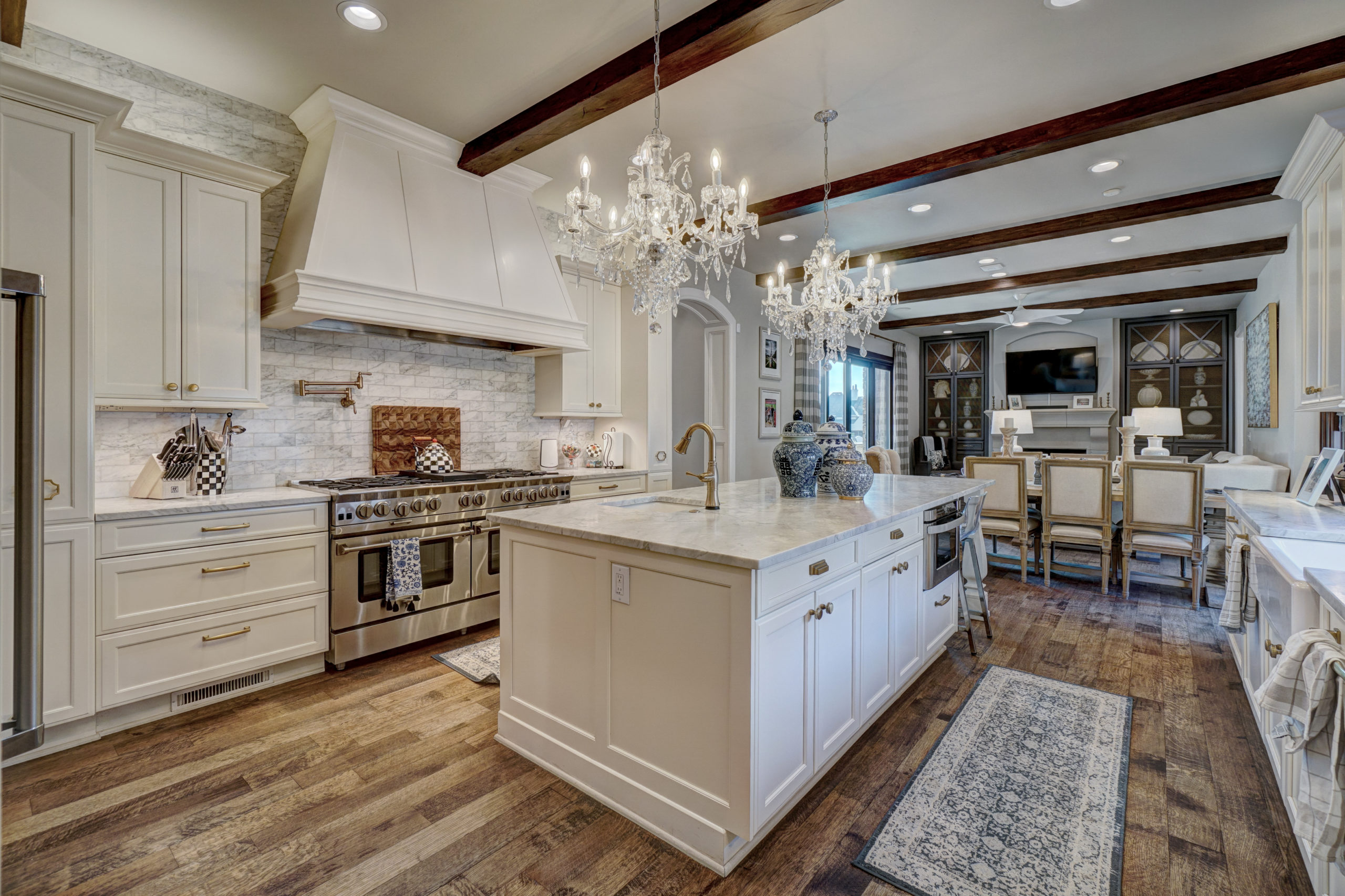 real estate photo of a large kitchen with white cabinets and wooden floors