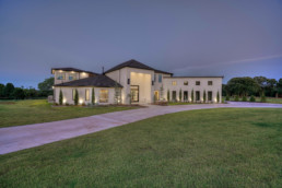 real estate photo of a large white house sitting on top of a lush green field