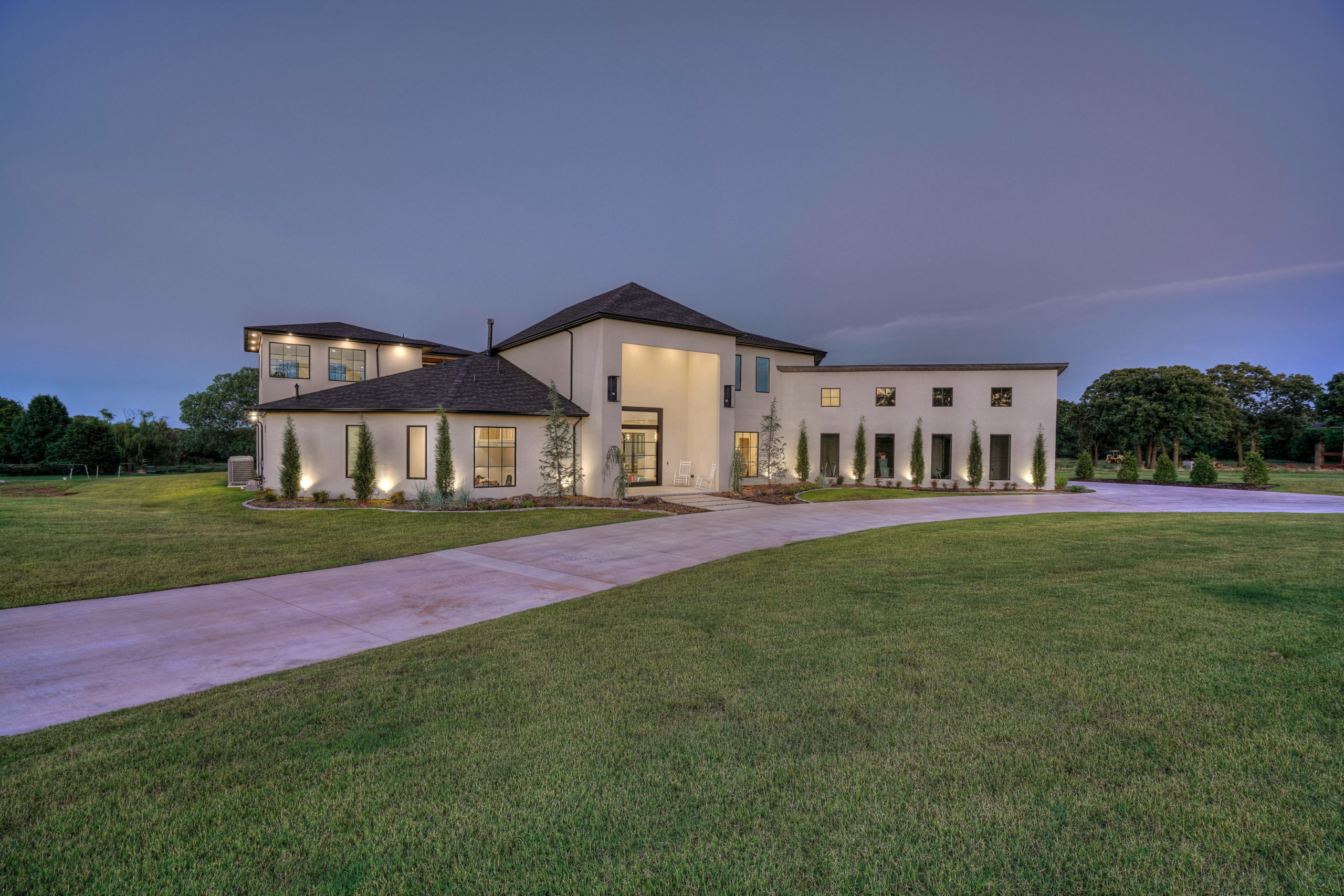 real estate photo of a large white house sitting on top of a lush green field