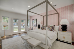 real estate photo of a bedroom with pink and white walls and a canopy bed