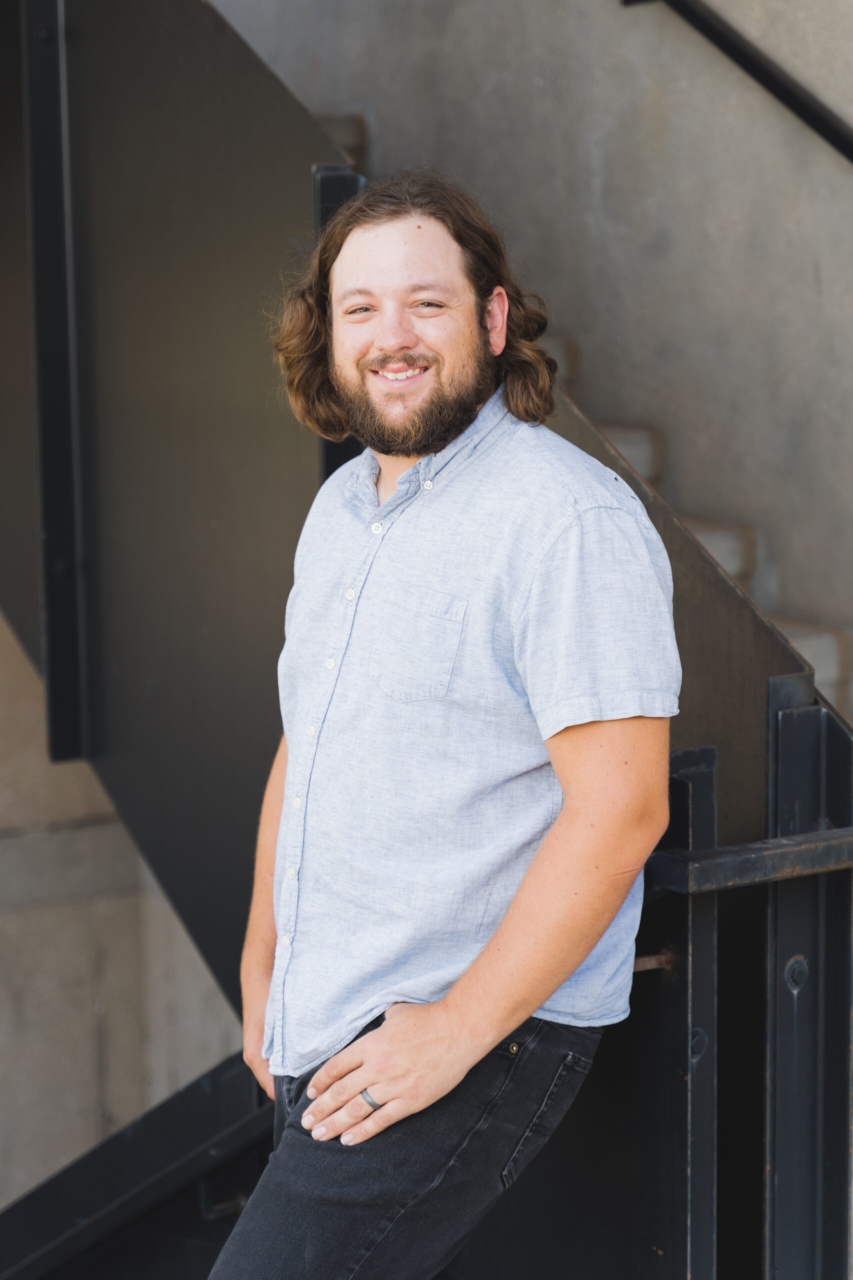 a man with a beard standing in front of a staircase